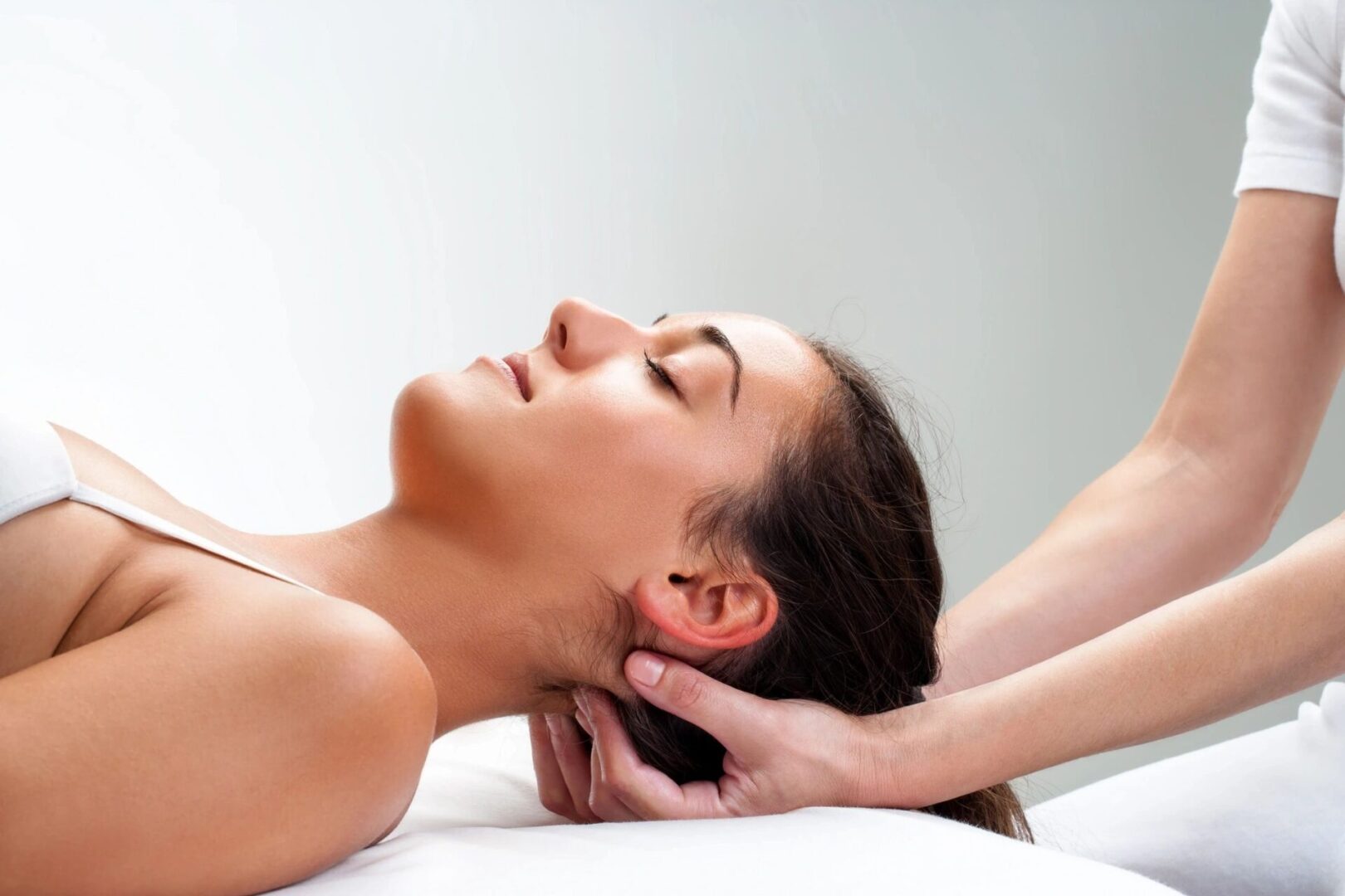 A woman getting her head massaged by a masseuse.