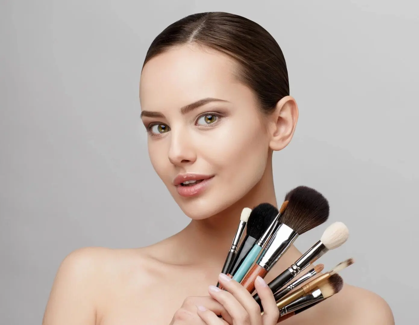 A woman holding makeup brushes in her hands.