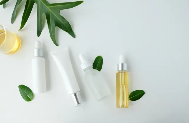 A white table topped with bottles of lotion and green leaves.