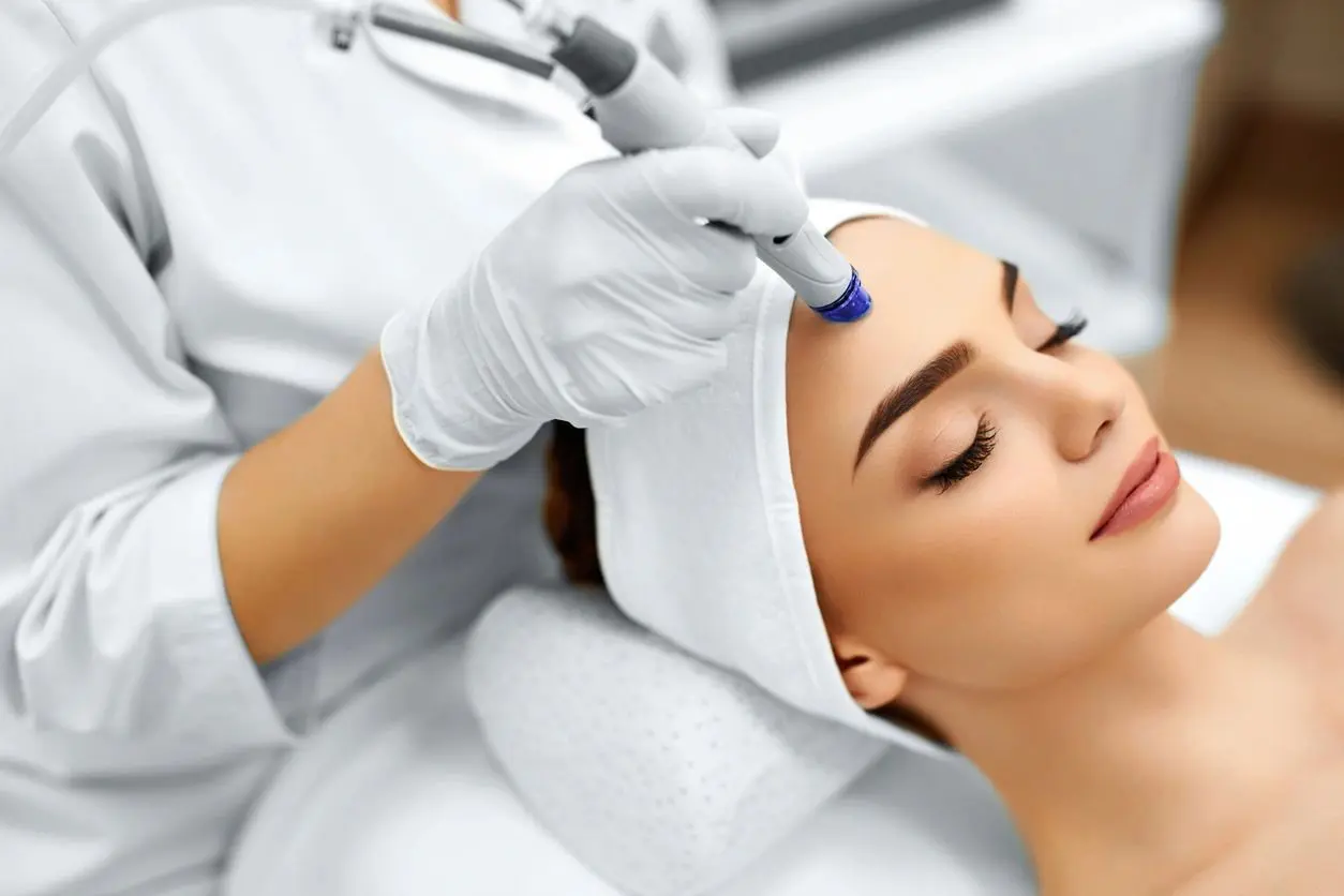 A woman getting her face cleaned with an electric device.